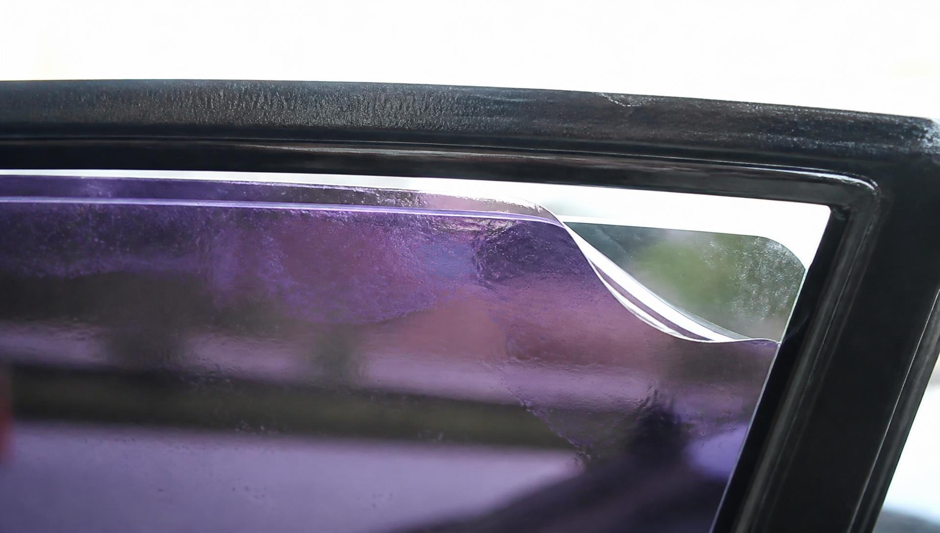 Close-up of failing window tint showing a light gap, lifted peeling corner, bubbles and purple discoloration