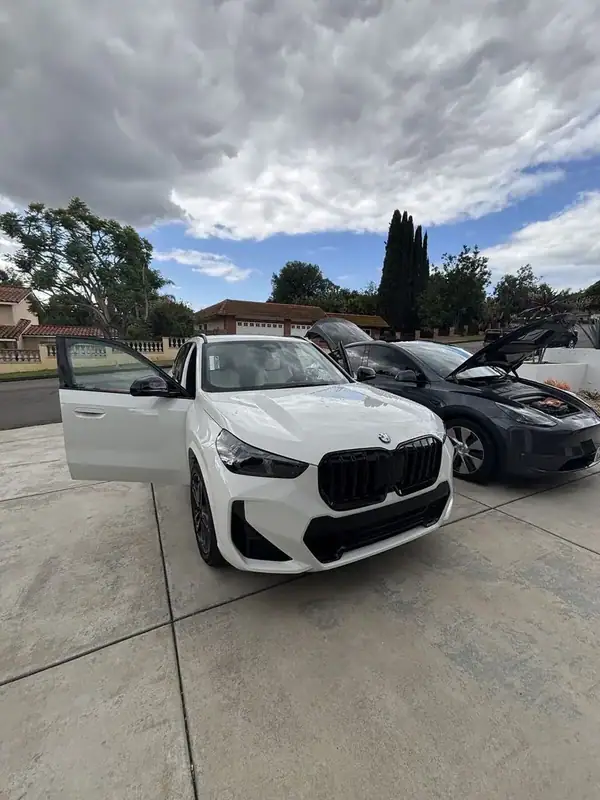 BMW X1 M-Sport (Alpine White) front view with door open showing freshly installed ceramic IR tint matching factory rear privacy glass — mobile window tinting San Diego