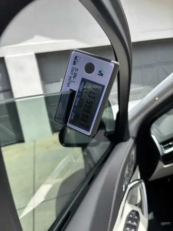 BestAutoTechs 3-in-1 tint meter on BMW X1 front window showing 99% UV rejection and 93% IR (infrared) heat rejection on installed HiTek ceramic IR film — verified on-site in San Diego