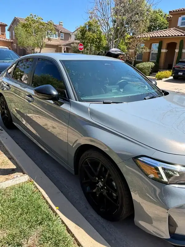 Sonic Gray Pearl 2025 Honda Civic Sport front three-quarter view with gloss black mirror caps and black alloy wheels after full carbon window tint install — mobile window tinting San Diego