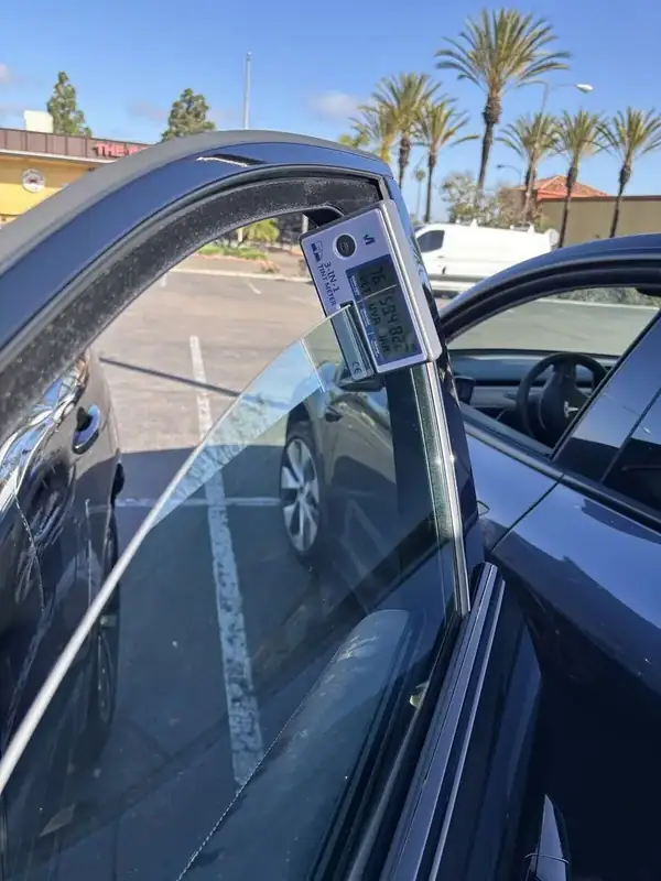 BestAutoTechs 3-in-1 tint meter on Jaguar F-Pace front window showing 76% VLT, 99% UV rejection, and 82% IR (infrared) heat rejection on installed HiTek ceramic IR film — verified on-site in San Diego