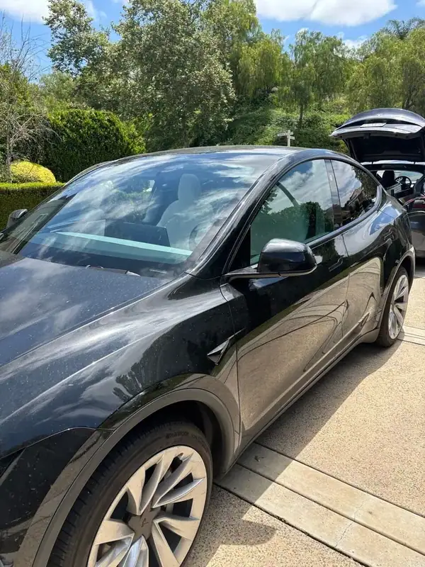 Black 2025 Tesla Model Y driver-side profile in the driveway after 70% windshield + front and 5% rear HiTek ceramic tint install — BestAutoTechs Orange County mobile