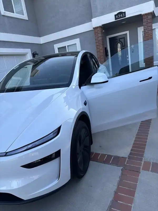Pearl White 2026 Tesla Model Y Highland Premium close-up of driver door and front quarter showing ceramic IR window tint and tinted panoramic glass roof — mobile window tinting San Diego